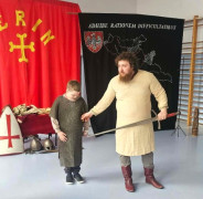Mężczyzna i chłopiec stroją obok siebie. Trwa pokazowa lekcja historyczna dotycząca czasów pierwszych Piastów 