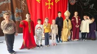 Grupa dzieci: chłopcy i dziewczynki stoją obok siebie. Wszyscy ubrani są w historyczne stroje 