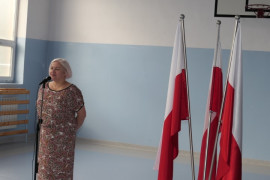 Kobieta podczas przemówienia. Po jej prawej stronie znajdują się flagi Polski