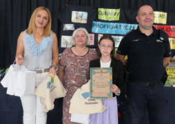 Dorośli i dziewczynka. Dziewczynka trzyma w ręku dyplom 