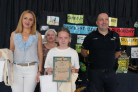 Dorośli i dziewczynka. Dziewczynka trzyma w ręku dyplom 