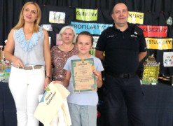 Dorośli i dziewczynka. Dziewczynka trzyma w ręku dyplom 
