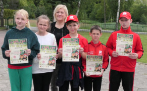 Dzieci i kobieta stoją obok siebie. Dzieci trzymają w dłoniach dyplomy