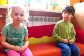 Dziewczynka i chłopiec siedzą na sofie 