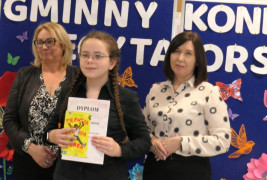 Dwie kobiety i dziewczynka. Dziewczynka trzyma w ręku dyplom oraz książkę 