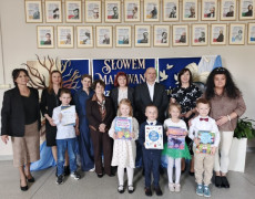 Grupa osób: dorośli i dzieci stoją obok siebie. Dzieci trzymają w dłoniach dyplomy 