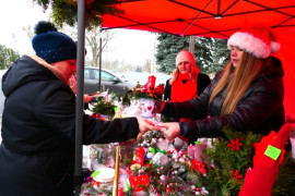 Stoisko wystawiennicze podczas kiermaszu bożonarodzeniowego, widoczne kobiety i ozdoby świąteczne 