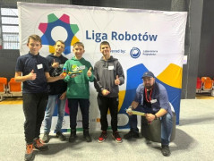 Czterej chłopcy i mężczyzna a tle banera z napisem "Liga robotów"
