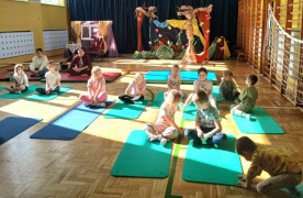 Dzieci siedzą na matach. Trwają zajęcia sportowe 