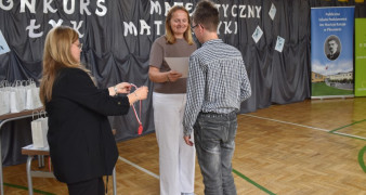 Dwie kobiety i chłopiec. Kobieta wręcza chłopcu dyplom 