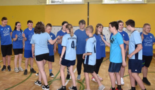 Grupa dzieci w niebieskich bluzkach podczas sportowego pozdrowienia 