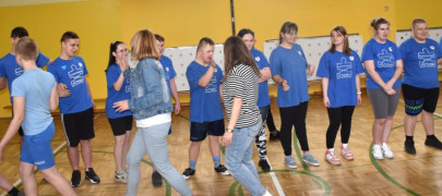 Grupa dzieci i dorosłych - większość w niebieskich bluzkach - podczas sportowego pozdrowienia