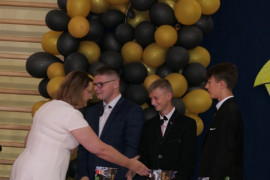 Kobieta - dyrektor szkoły - gratuluje uczniom 