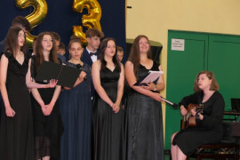 Grupa uczennic podczas części artystycznej. Jedna z nich gra na gitarze