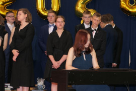 Uczniowie podczas występów artystycznych. Jedna z uczennic gra na pianinie