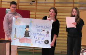 Dwie uczennice i uczeń stoją obok siebie. Dziewczynka i chłopiec trzymają plakat