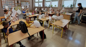 Dzieci siedzą w szkolnych ławkach 