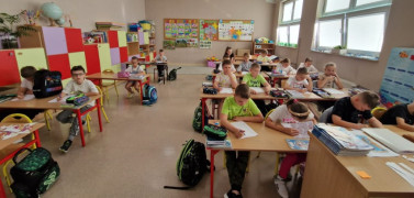 Dzieci siedzą w szkolnych ławkach 