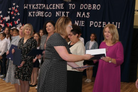 Grupa osób - dyrektor wręcza nagrodę nauczycielowi 