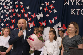 Grupa osób - wójt Gminy Radomsko dziękuje pracownikom PSP w Strzałkowie za trud w wychowaniu przyszłych pokoleń. W ręku trzyma bukiet kwiatów