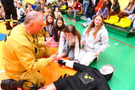 Uczniowie w asyście strażaka zgłębia zasady udzielania pierwszej pomocy