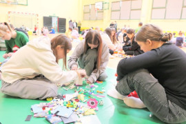 Trzy nastolatki siedzą na podłodze i układają kocki lego