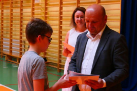 Chłopiec z rąk mężczyzny odbiera dyplom 