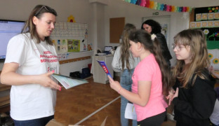 Kobieta wręcza dzieciom książeczki 