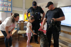 Dwaj mężczyźni w mundurach. Kobieta i dziewczynka. Dziewczynka głaszcze psa