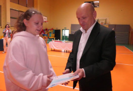Mężczyzna wręcza dziewczynce dyplom 