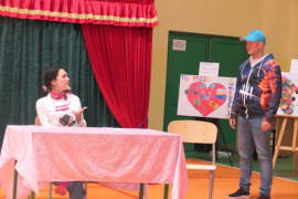 Kobieta i mężczyzna. Kobieta siedzi przy stole. Mężczyzna stoi 