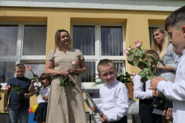 Grupa osób, dorośli i dzieci. Dzieci otrzymują upominki książkowe 