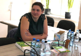 Kobieta siedzi przy stole. Przez kobietą leży Apteczka Pierwszej Pomocy Emocjonalnej 