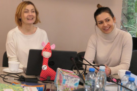 Dwie uśmiechnięte kobiety siedzą przy stole. Kobiety prowadzą szkolenie