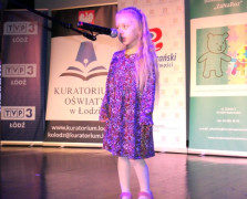 Dziewczynka stoi na scenie przy mikrofonie 