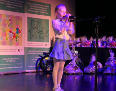 Dziewczynka stoi na scenie przy mikrofonie