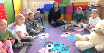 Dzieci podczas zajęć. Dzieci siedzą w kółku na dywanie 