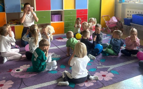 Dzieci siedzą na dywanie. Dzieci uczestniczą w warsztatach 