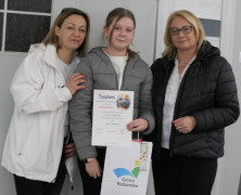 Dwie kobiety i dziewczynka. Dziewczynka trzyma w ręku dyplom 