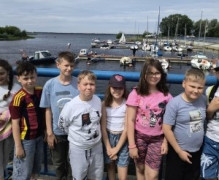 Dzieci stoją obok siebie. Za nimi widoczny jest zalew 