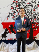 Chłopiec w garniturze. Chłopiec trzyma w ręku dyplom 
