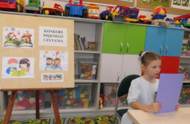 Dziewczynka siedzi w ławce i czyta tekst