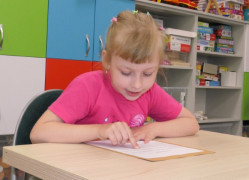 Dziewczynka siedzi w ławce i czyta tekst