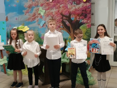 Piątka dzieci: chłopcy i dziewczynki stoją obok siebie. Dzieci trzymają w dłoniach dyplomy  