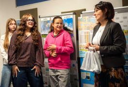 Kobieta i trzy dziewczynki stoją obom siebie. Kobieta trzyma w ręku torby prezentowe i rozmawia z dziewczynkami