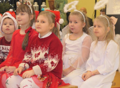 Dziewczynki w białych i czerwonych strojach siedzą obok siebie