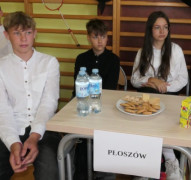 Dziewczyna i dwaj chłopcy siedzą obok siebie przy stoliku 