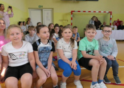 Grupa dzieci siedzi na ławce obok siebie
