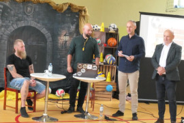 Czterej mężczyźni. Trzej mężczyźni stoją, jeden siedzi przy stoliku 