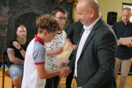 Mężczyzna wręcza chłopcom dyplom 